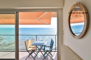 Ein Balkon mit Tisch und Stühlen, mit Blick auf das Meer.