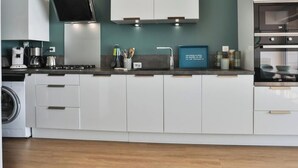 A modern kitchen with white cabinets, a built-in oven, and a coffee maker. - Brasilia - Vue mer d’exception aux Sables, balcon & plage (Les Sables-d´Olonne)