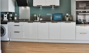 Eine moderne Küche mit weißen Schränken, einem eingebauten Backofen und einer Kaffeemaschine.