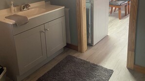 Et badeværelse med vask, spejl og træskabe.