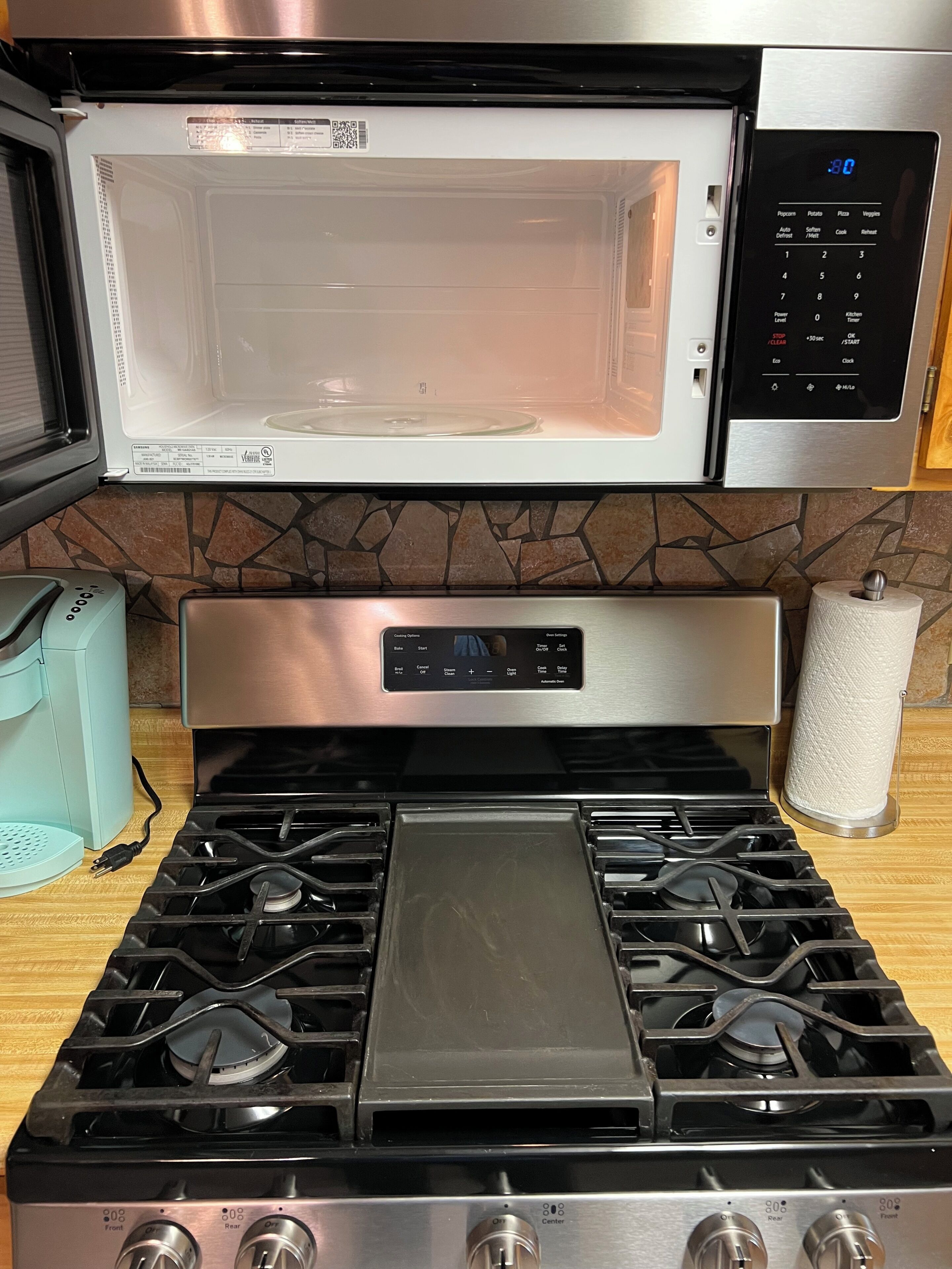 Une cuisine équipée d  ’un four à micro-ondes, d’une cuisinière et d’un porte-rouleau en papier.