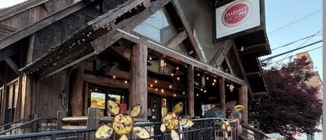 A rustic building with a wooden facade, a sign reading 'HARVEST ON MAIN ST.', and a metal fence in front.