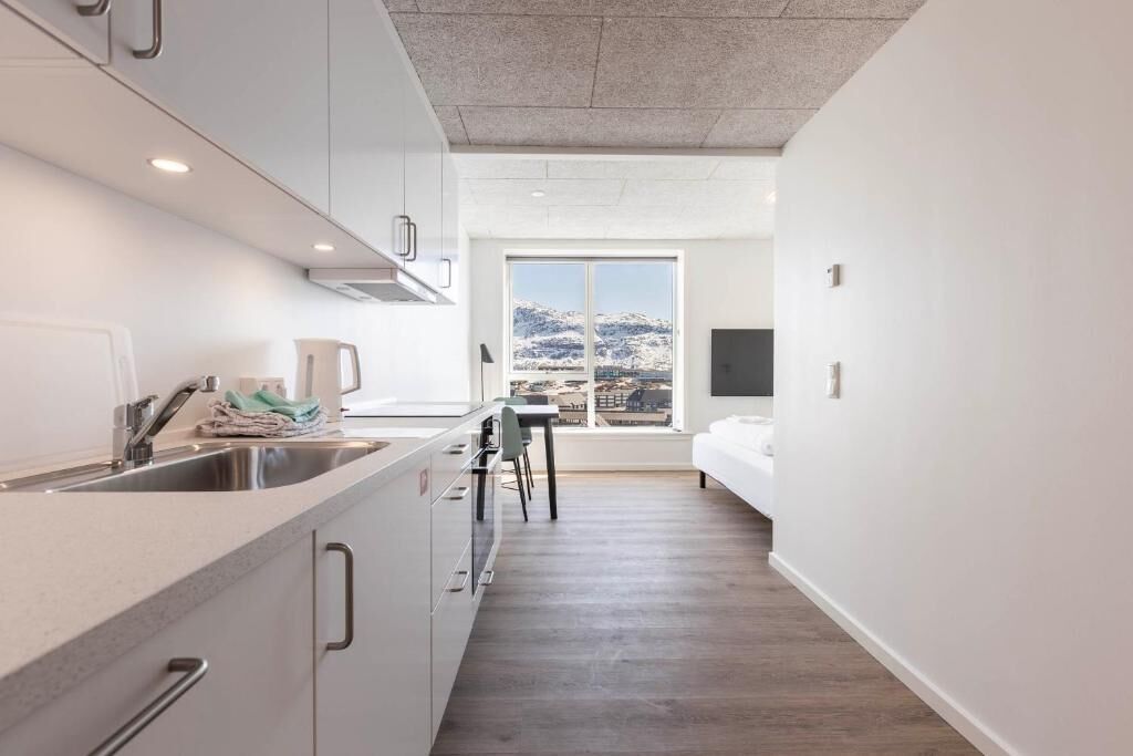 Eine moderne Küche mit großem Fenster, einem Essbereich und einem Bett.