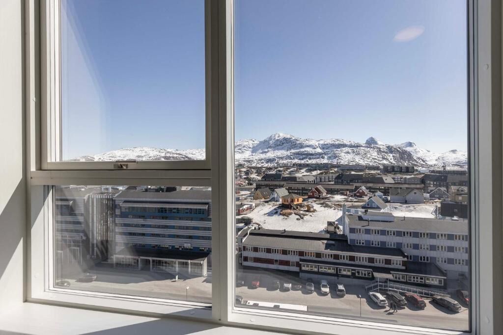 A window view of a building with a snowy mountain backdrop.