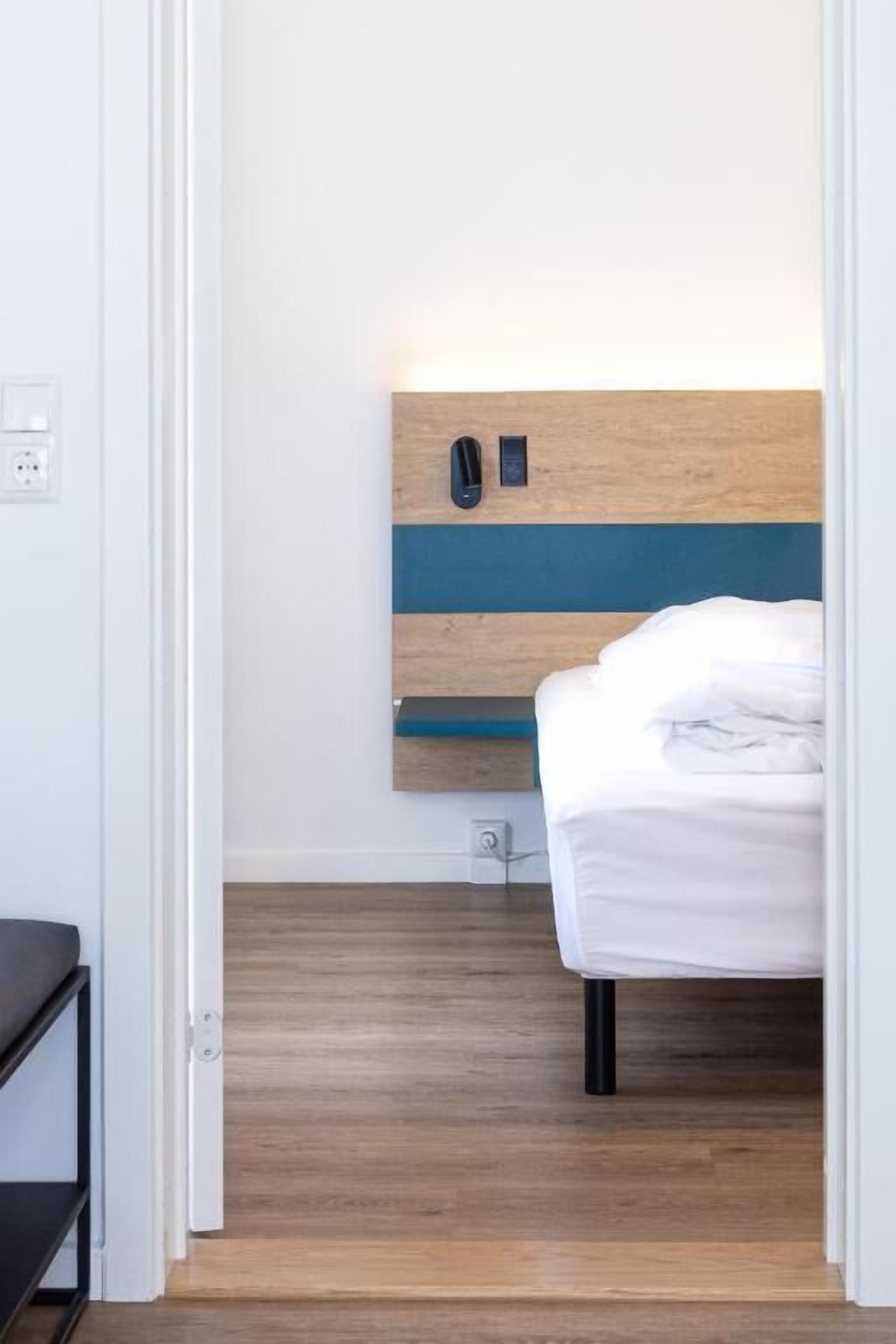 Ein Schlafzimmer mit Bett, Nachttisch und fest montiertem Telefon.