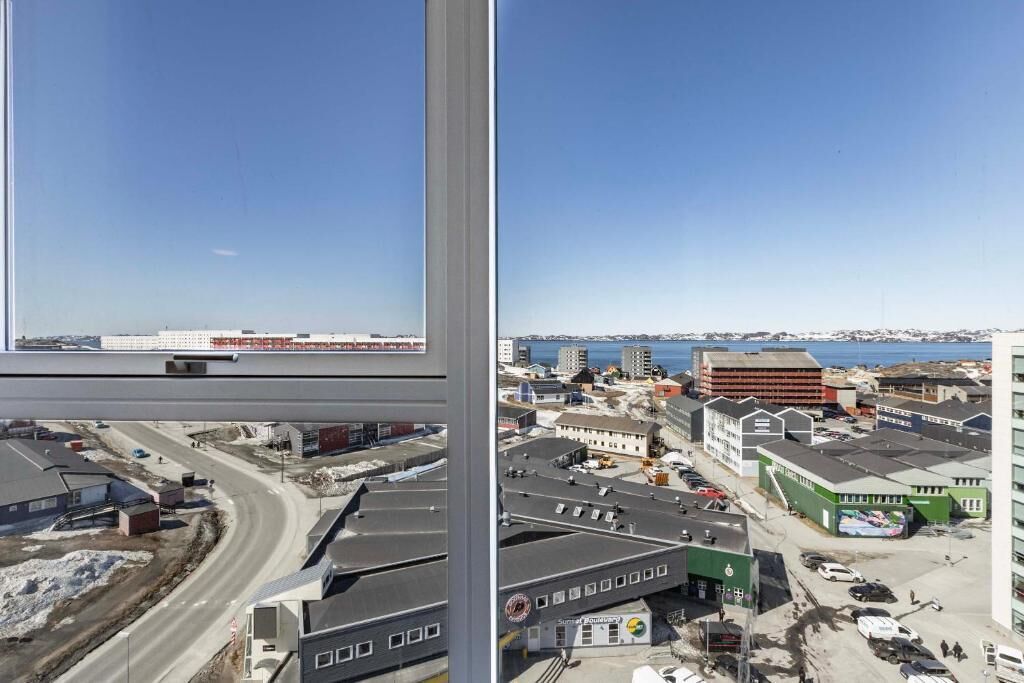 A high-rise building with a view of a coastal town, including roads and buildings.