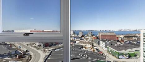 A high-rise building with a view of a coastal town, including roads and buildings.