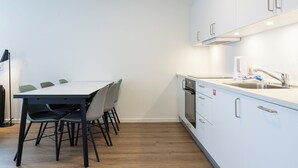 Una cocina moderna con armarios blancos, un lavamanos de acero inoxidable y un comedor con mesa y sillas.