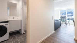 Un apartamento moderno con lavandería, comedor y un amplio ventanal con vistas a la montaña.