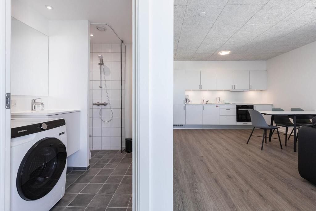 A modern kitchen with white cabinets, a dining area with a table and chairs, and a laundry room with a washing machine.