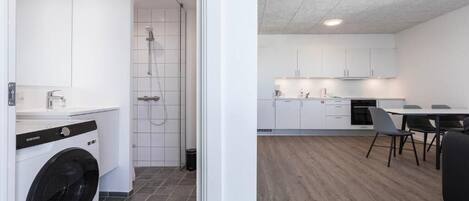 A modern kitchen with white cabinets, a dining area with a table and chairs, and a laundry room with a washing machine.