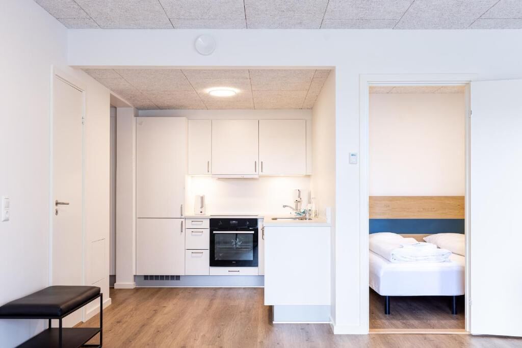 Eine moderne Wohnung mit einer Küchenzeile, einem Bett und einer Sitzbank.