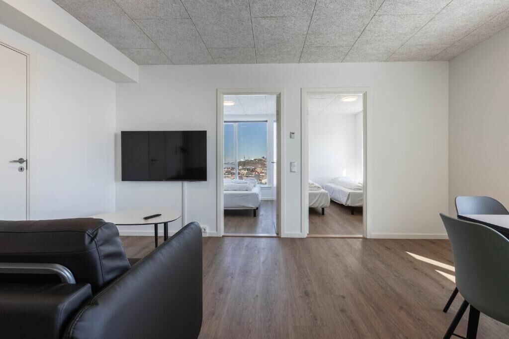 Ein modernes Hotelzimmer mit Flachbildfernseher, einem Bett, einem Schreibtisch und einem Sessel.