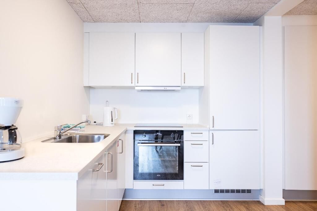 A modern kitchen with white cabinets, a built-in oven, and a coffee maker.