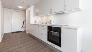 Une cuisine moderne avec des meubles blancs, un four encastré et une machine à café.