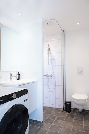 Ein modernes Badezimmer mit Waschmaschine, Duschkabine aus Glas und Toilette.