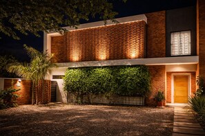 Un bâtiment moderne à deux étages, doté d’une façade en briques, d’un mur d’escalade végétalisé et d’une entrée bien éclairée.