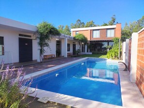 Une maison moderne dotée d’une piscine, d’un patio couvert et d’une façade en briques.