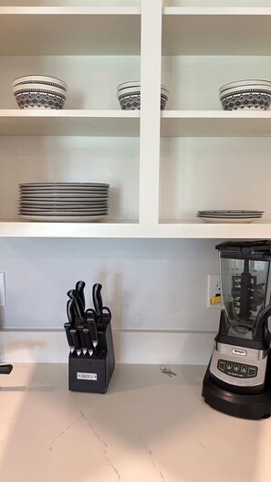 Eine Küche mit weißen Schränken, einem Mixer und einem Messerblock.