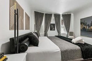 Ein modernes Hotelzimmer mit einem großen Bett, einer Sitzecke und Blick auf die Stadt.