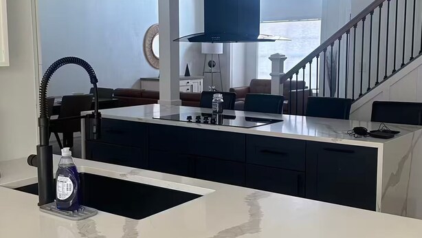 A modern kitchen with a central island, a built-in stove, and a large window. - Beach House (Indialantic)