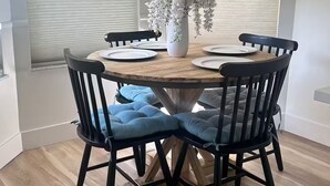 A dining table with chairs, a hanging light fixture, and a vase with flowers. - Beach House (Indialantic)