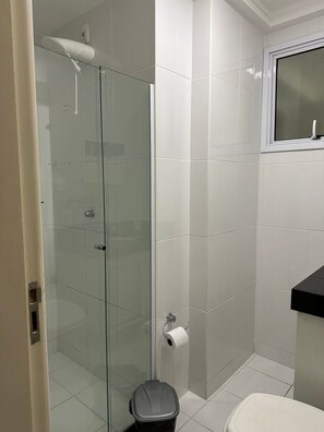 Ein Badezimmer mit Duschkabine, Toilette und Waschbecken mit Spiegel darüber.