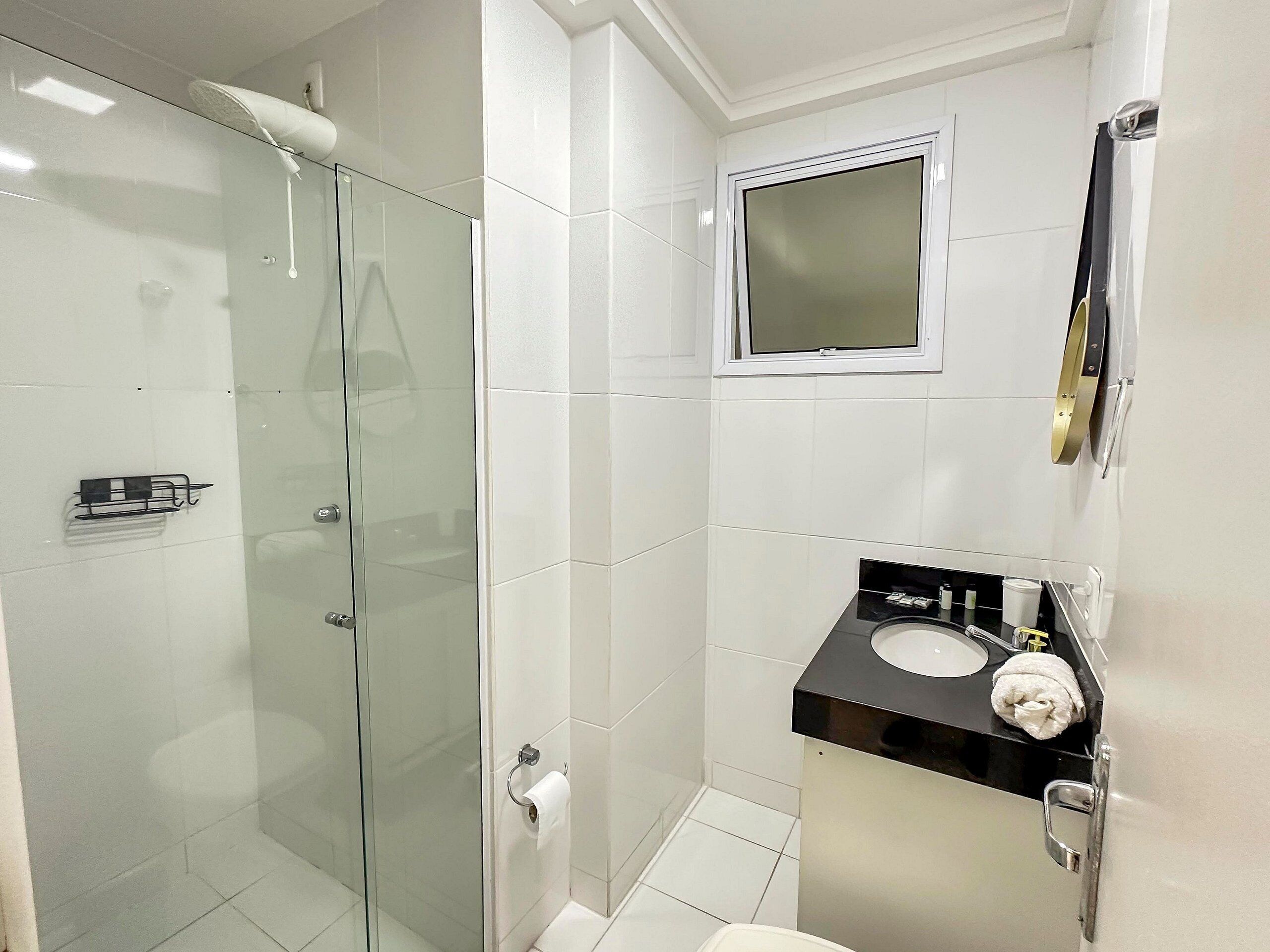 A modern bathroom with a glass shower enclosure, a black sink vanity, and a mirror above the sink.