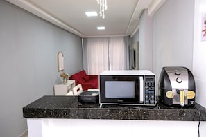 A kitchenette with a microwave, coffee machine, and a small refrigerator. - 3 bedrooms with the best location in Guarapari (Guarapri)