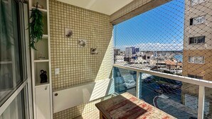 En balkon med udsigt over bybilledet, en flisebeklædt væg med dekorative detaljer, og et lille bord.