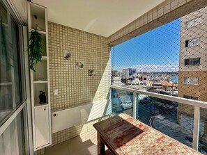 A balcony with a view of a cityscape, a tiled wall with decorative elements, and a small table. - 3 bedrooms with the best location in Guarapari (Guarapri)