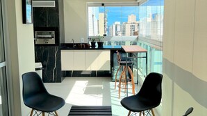 Eine moderne Küche mit großem Fenster, einem eingebauten Ofen und einem Essbereich mit Stühlen und Tisch.