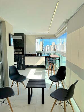 Eine moderne Küche mit großem Fenster, einem eingebauten Ofen und einem Essbereich mit Stühlen und Tisch.