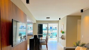 Ein modernes Wohnzimmer mit Flachbildfernseher, Essbereich und einem Balkon mit Blick.