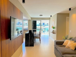 Ein modernes Wohnzimmer mit Flachbildfernseher, Essbereich und einem Balkon mit Blick.
