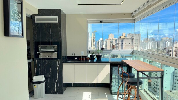 Eine moderne Küche mit Einbauofen, Spüle und Fenster mit Blick auf eine Stadtlandschaft.