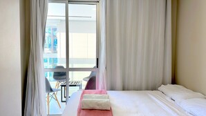 Ein Hotelzimmer mit Bett, einem Fenster mit Vorhängen und Blick nach draußen.