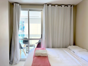 Ein Hotelzimmer mit Bett, einem Fenster mit Vorhängen und Blick nach draußen.