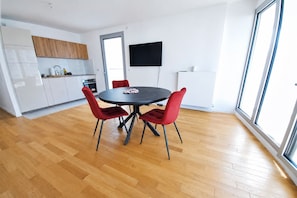 A modern kitchen with white cabinets, a dining area with a round table and red chairs, and a large window providing natural light. - Modern & Smart Paris 13 Bibliothèque François Mitterrand (Paris)