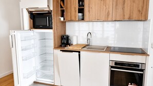 Eine kompakte Küche mit integriertem Mikrowellenherd, einer Kaffeemaschine, einem Spülbecken und einem Geschirrspüler.