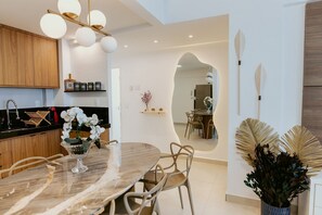 A modern kitchen with wooden cabinets, a marble dining table, and a chandelier. - Sea Front - 3Q Wonderful and cozy (Vila Velha)