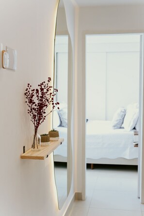 A modern hotel room with a large mirror, a bedside table with a vase of dried flowers, and a neatly made bed. - Sea Front - 3Q Wonderful and cozy (Vila Velha)