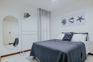Ein Schlafzimmer mit Bett, Spiegel, Dusche und Wandbildern.