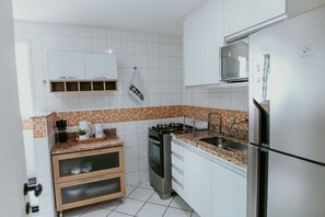 Eine Küche mit weißen Schränken, einem Herd, einem Kühlschrank und einer Arbeitsplatte mit einer Kaffeemaschine.