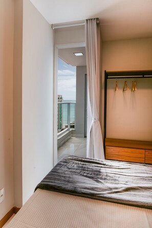 Ein Hotelzimmer mit Bett, einem Holzschrank, Meerblick und einem Balkon.