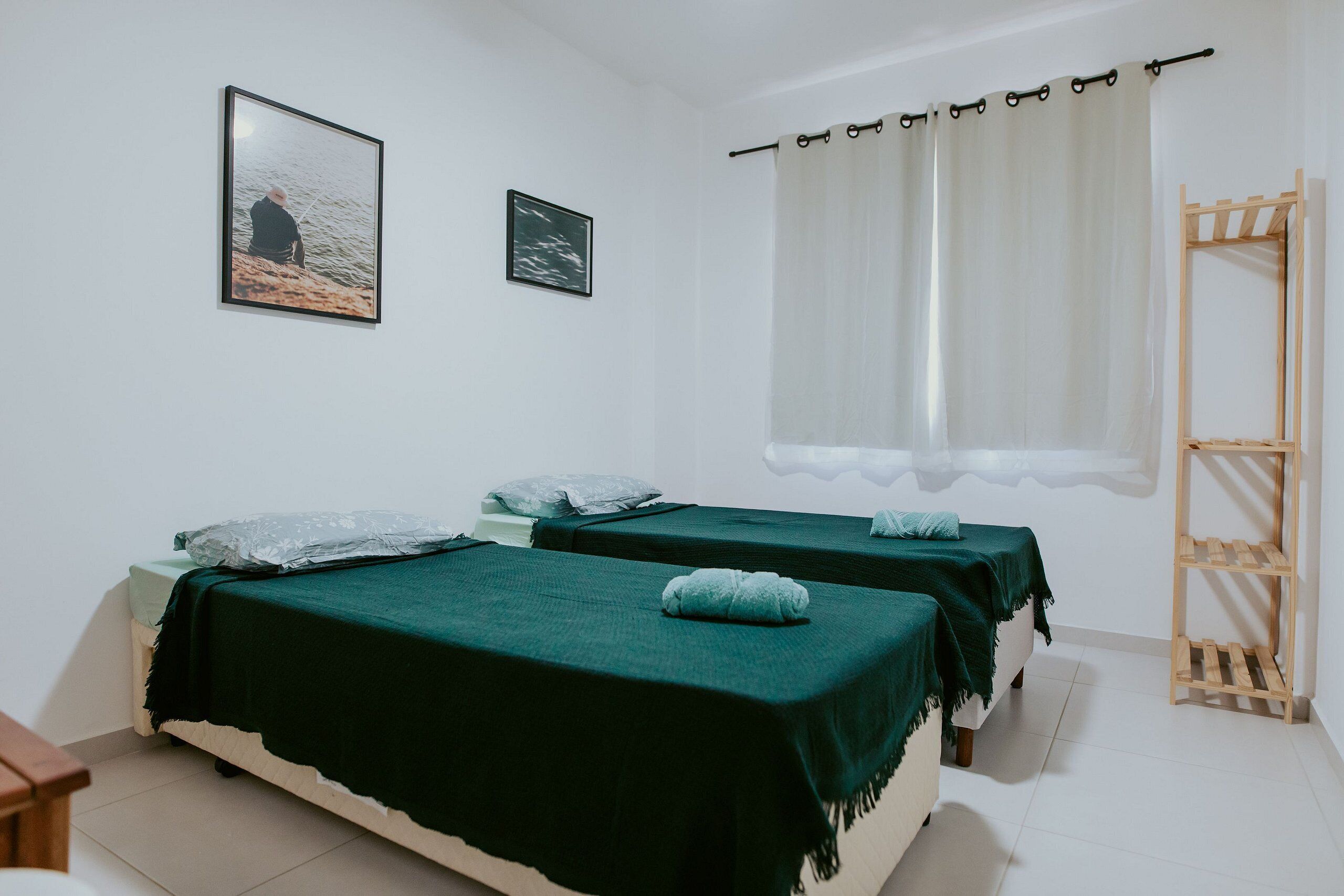 Una habitación con dos camas, un estante de madera y una ventana con cortinas.