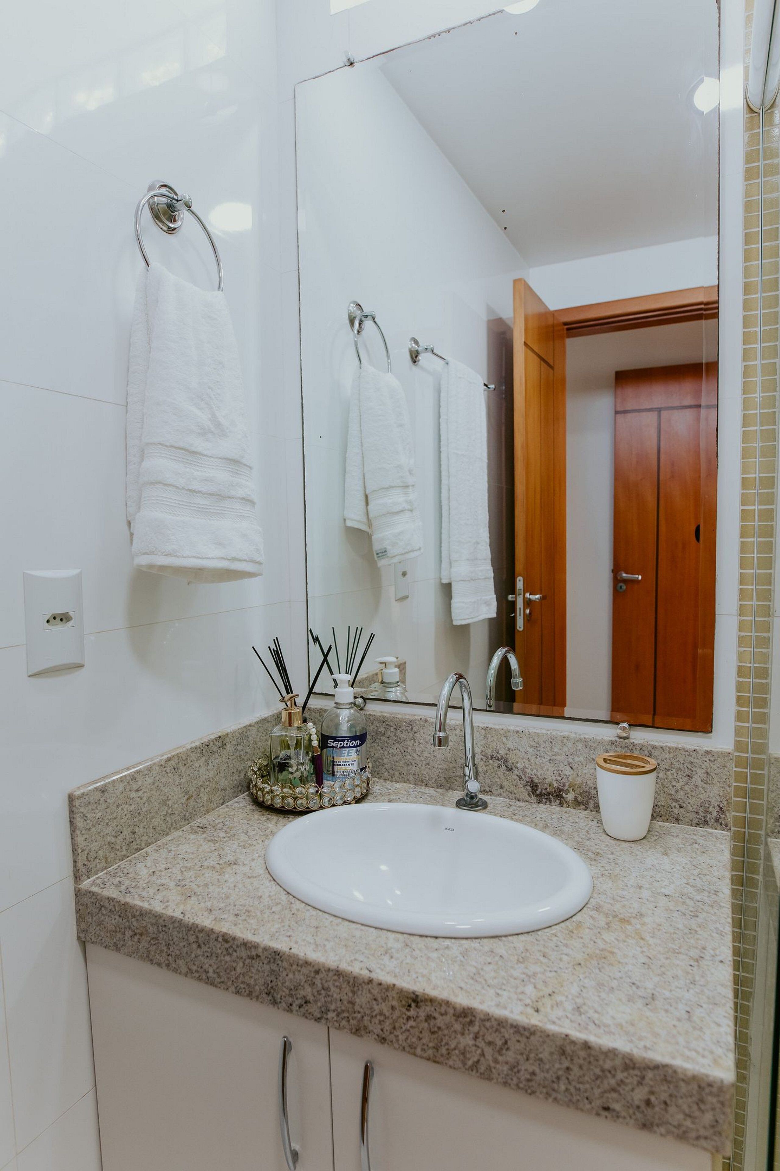 Un baño con lavamanos blanco, un espejo y una puerta de madera.