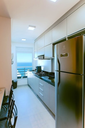 Eine moderne Küche mit Edelstahlgeräten, Meerblick und einem Balkon.