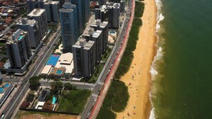 An aerial view of a coastal city with high-rise buildings, a beach, and a road running parallel to the shore. - Modern apartment with incredible sea views (Vila Velha)