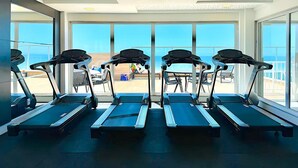 A gym with treadmills and large windows overlooking a beach. - Modern apartment with incredible sea views (Vila Velha)